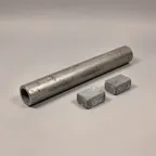 Used lead scrap: a short length of lead pipe and two small grey lead weights.